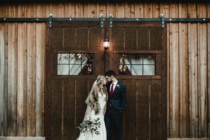 Bride and groom in front of barn at The Wheeler House